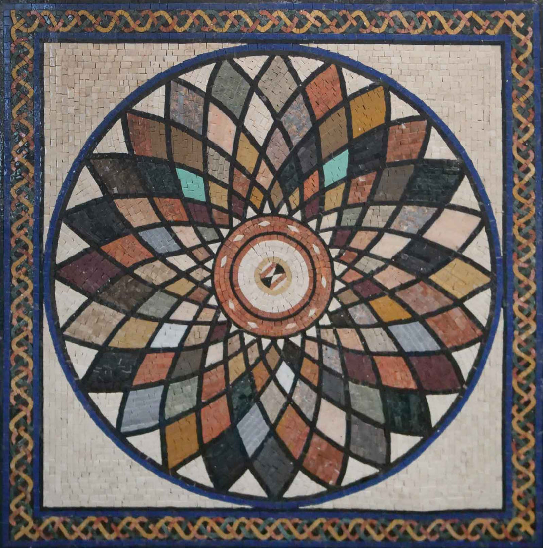 Circular mosaic rosette of overlapping petals in muted greens, reds and ochres inside a blue border