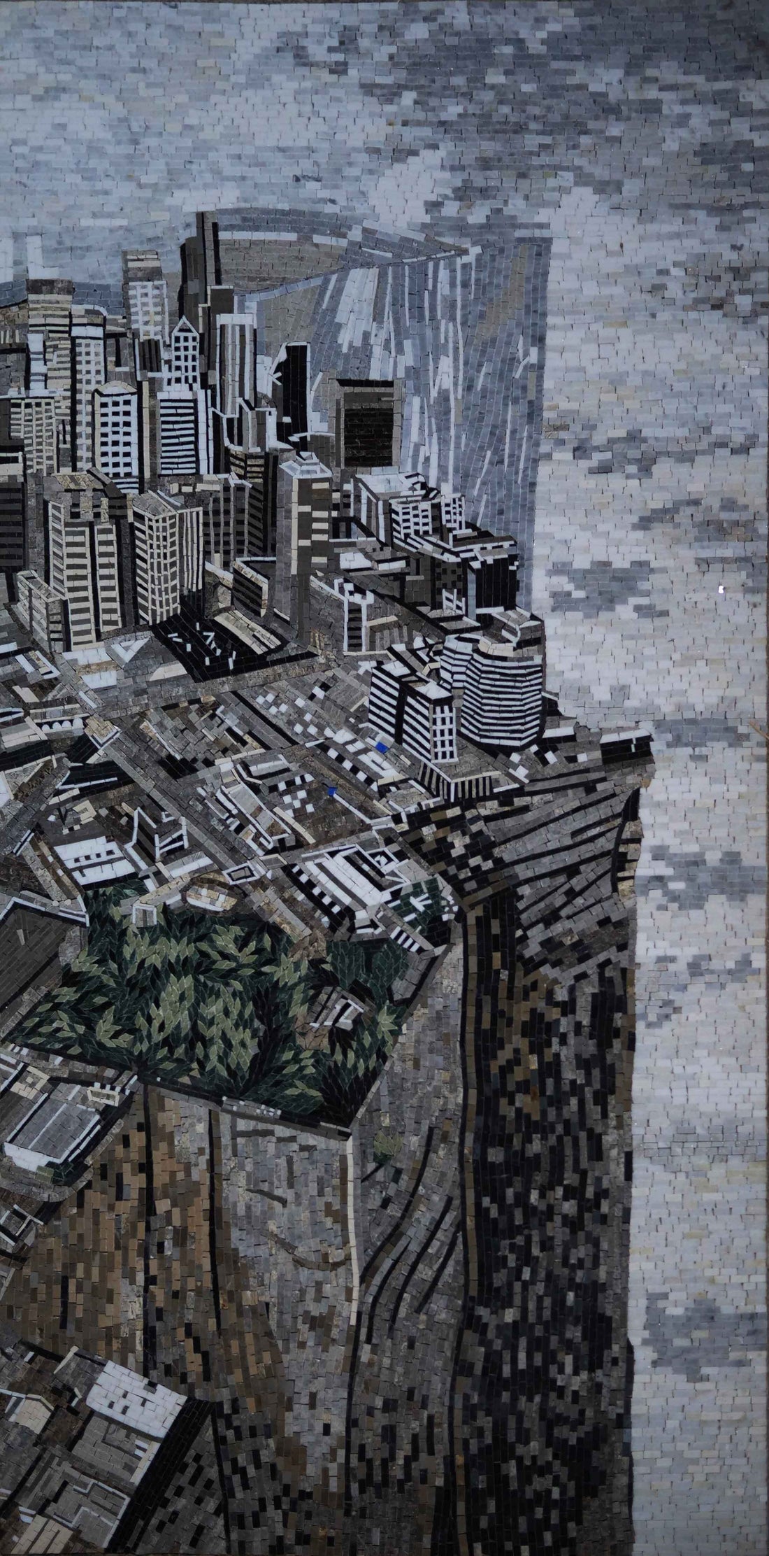 Greyscale mosaic of a dense high-rise city seen from above, tower blocks crowding a narrow street canyon