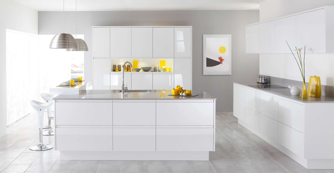 All-white modern kitchen with a central island, pendant light and small yellow accents