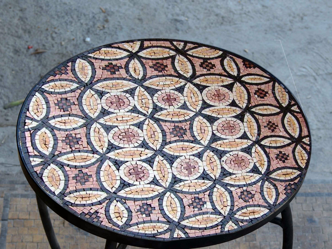 Round mosaic table top in pink, cream and black marble with an interlocking circle pattern, on a wrought-iron base