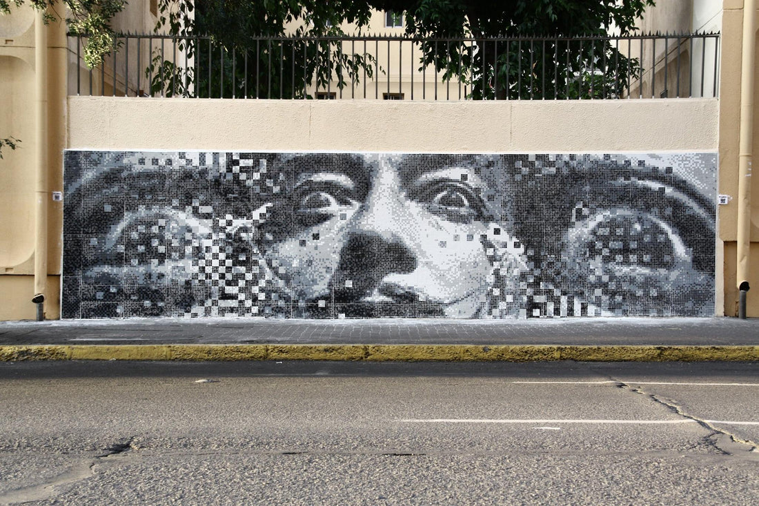 Large black and white mosaic face covering a street wall