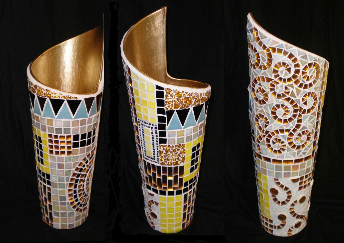 Three tall mosaic-covered vases with gilded interiors, photographed against a black backdrop