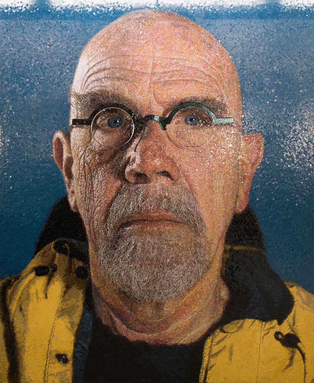 Mosaic self-portrait of Chuck Close in glasses against a deep blue ground